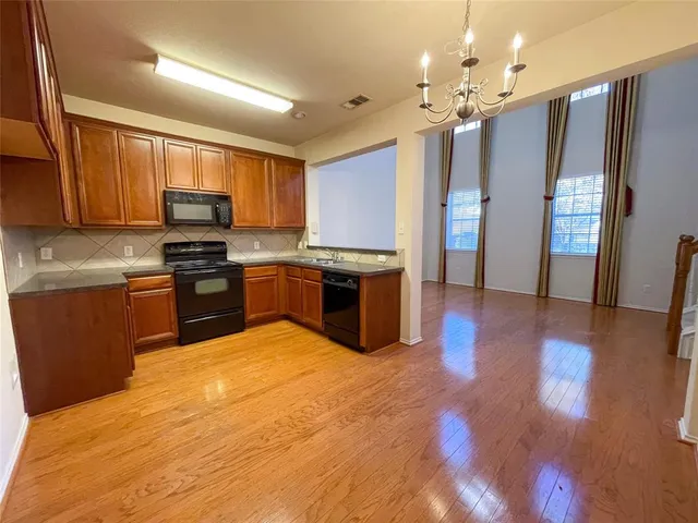 a kitchen with stainless steel appliances granite countertop a refrigerator a stove top oven a sink dishwasher and wooden cabinets