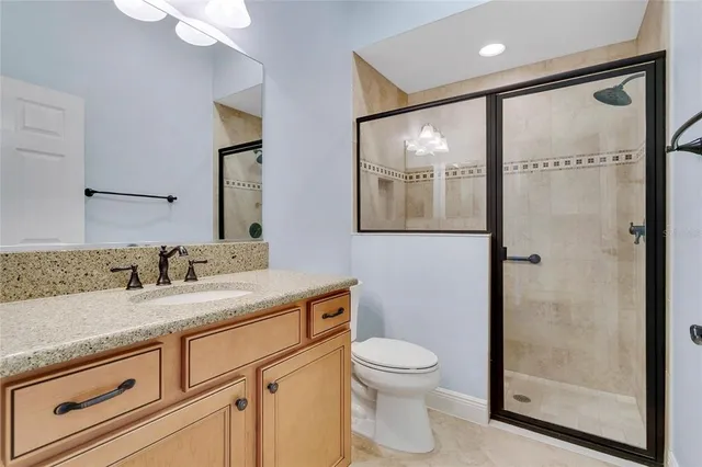 a bathroom with a granite countertop sink mirror vanity and toilet