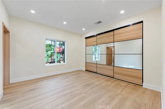 a view of a hallway with wooden floor and a bathroom
