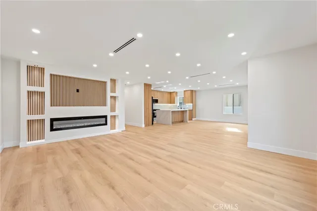 a view of an empty room with kitchen and window
