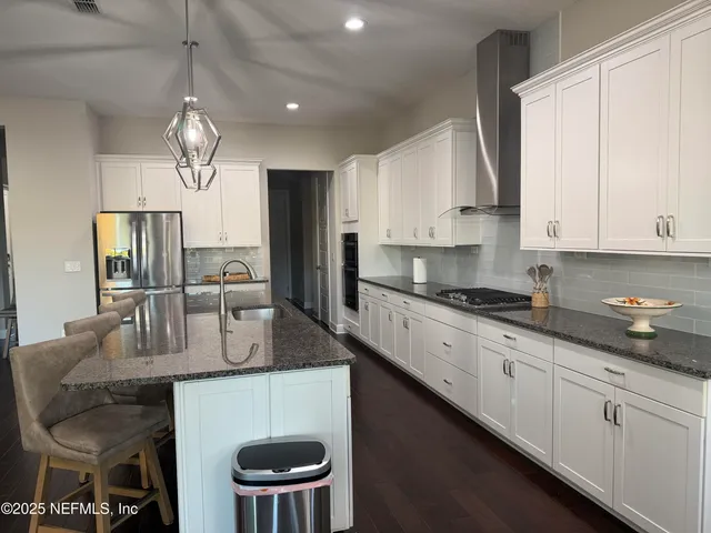 a kitchen with stainless steel appliances a table chairs refrigerator and microwave