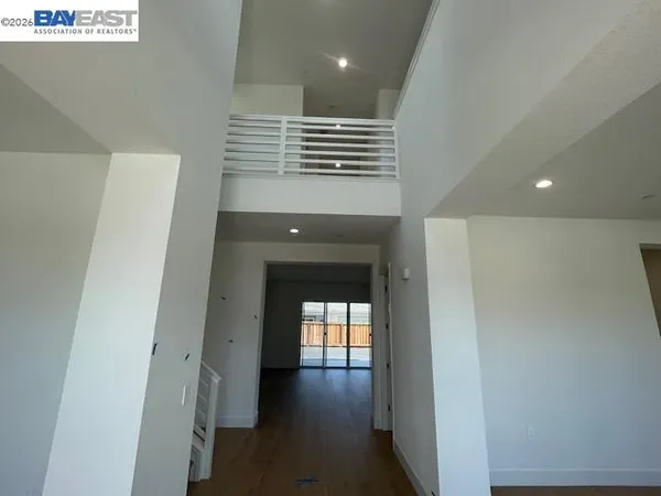 a view of a hallway to an empty room with wooden floor and a window
