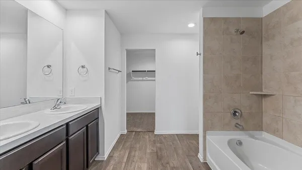 a bathroom with a tub sink shower and two mirror