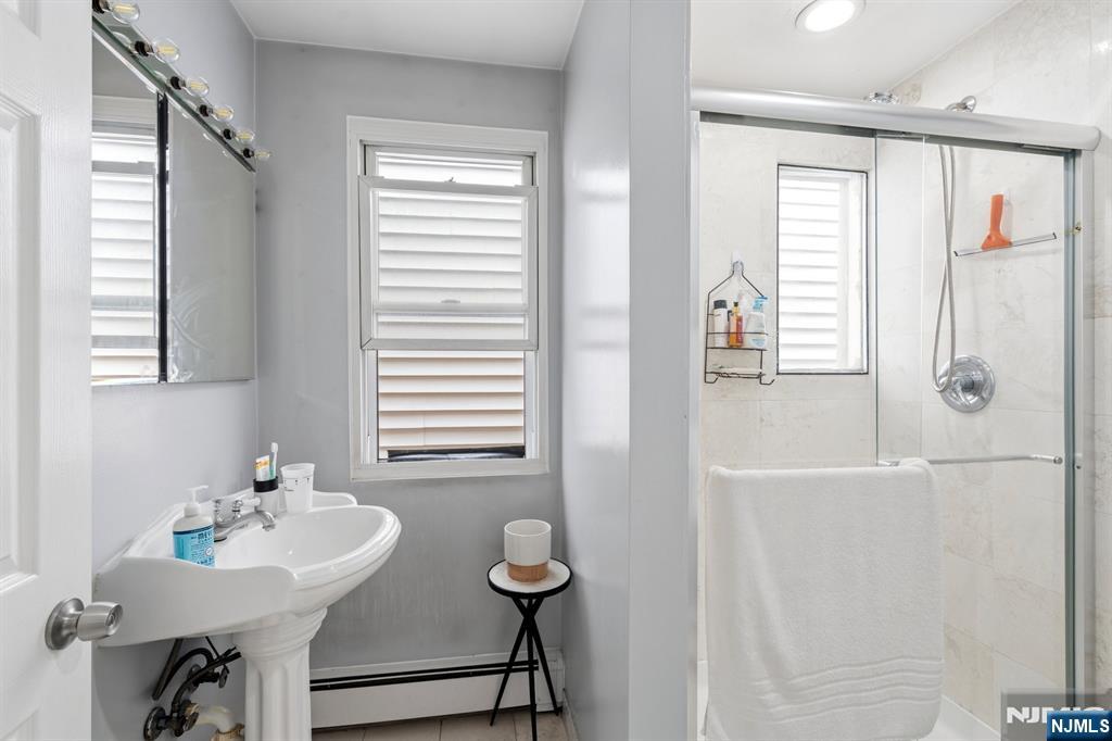 258 Old River Road Edgewater, NJ 07020 - Photo 18 of 32 a bathroom with a sink a mirror and a shower