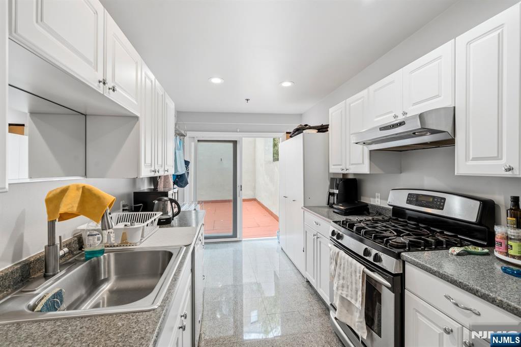 258 Old River Road Edgewater, NJ 07020 - Photo 7 of 32 a kitchen with stainless steel appliances a sink a stove and a refrigerator with wooden floor