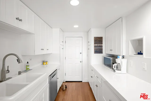 a kitchen with a sink a counter top space stainless steel appliances and cabinets