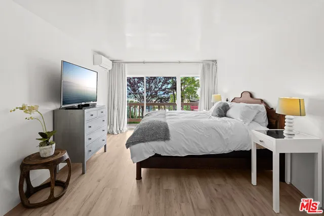 a bedroom with a bed and a flat tv screen on dresser