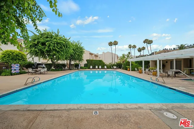 a view of a swimming pool with lawn chairs and plants