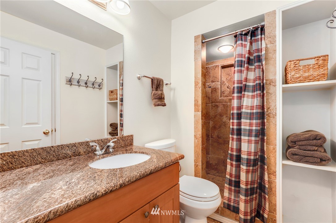 24118 2nd Place West Bothell, WA 98021 - Photo 21 of 25 a bathroom with a granite countertop sink a toilet a mirror a shower and a bathtub
