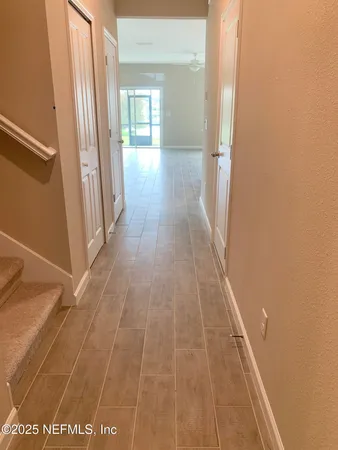 a view of a hallway with wooden floor and a bathroom