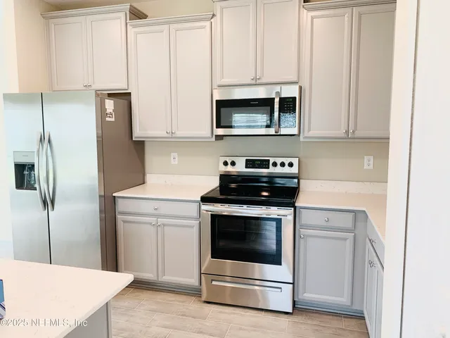 a kitchen with white cabinets and stainless steel appliances