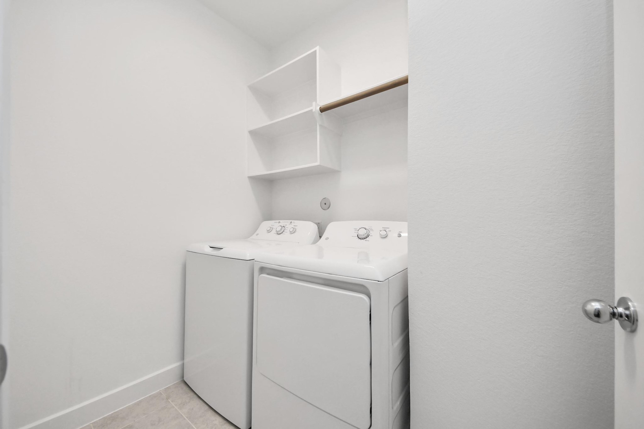 18527 Centro Row Conroe, TX 77385 - Photo 37 of 44 This bright laundry suite is engineered for efficiency, with an integrated hanging rod and open shelving to keep everything organized.