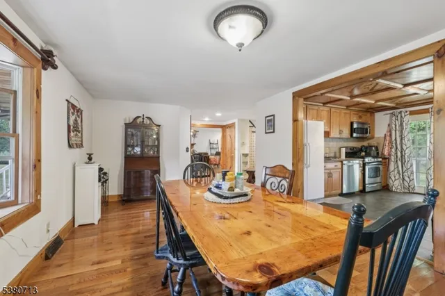 a kitchen with stainless steel appliances granite countertop a stove a sink dishwasher and white cabinets with wooden floor