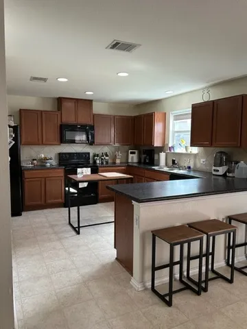 a kitchen with stainless steel appliances granite countertop a stove a sink a microwave a refrigerator and a microwave