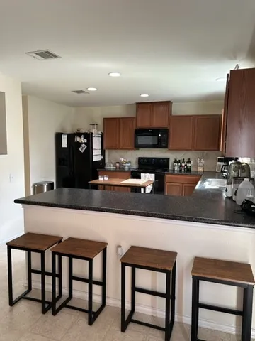 a kitchen with stainless steel appliances granite countertop a table chairs sink and microwave