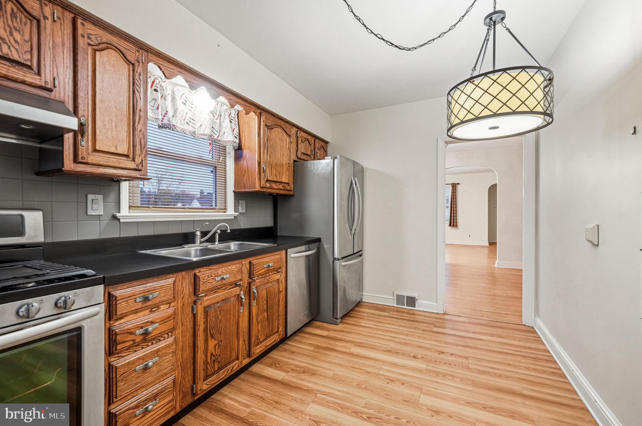 101 6th Avenue Mount Ephraim, NJ 08059 - Photo 13 of 27 a kitchen with stainless steel appliances granite countertop a refrigerator a sink dishwasher a stove and white countertops with wooden floor