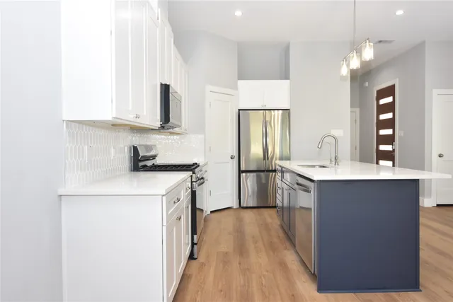 a view of kitchen and empty room with wooden floor