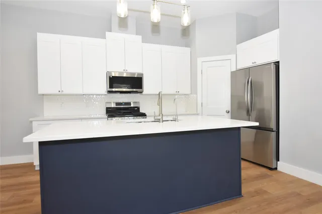 a kitchen with kitchen island white cabinets and stainless steel appliances