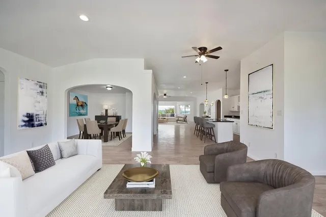 a living room with furniture kitchen view and a chandelier