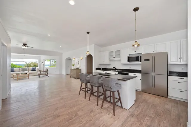 a kitchen with stainless steel appliances a stove a refrigerator a sink a oven a dining table with chairs