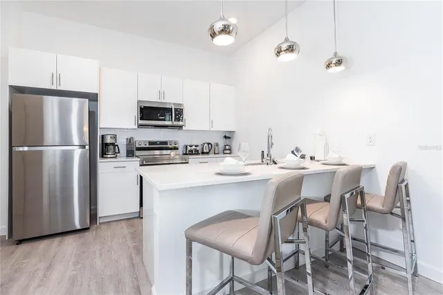 a kitchen with stainless steel appliances a microwave a stove a sink dishwasher a refrigerator with a dining table and chairs