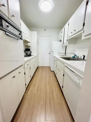 a large white kitchen with sink and stainless steel appliances