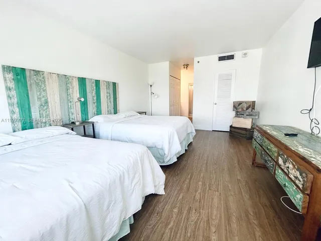 a bedroom with two beds and a dresser next to a window
