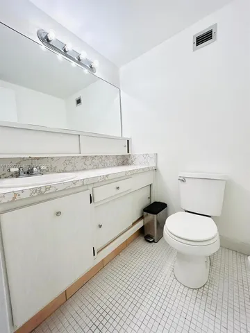 a bathroom with a granite countertop toilet sink and mirror
