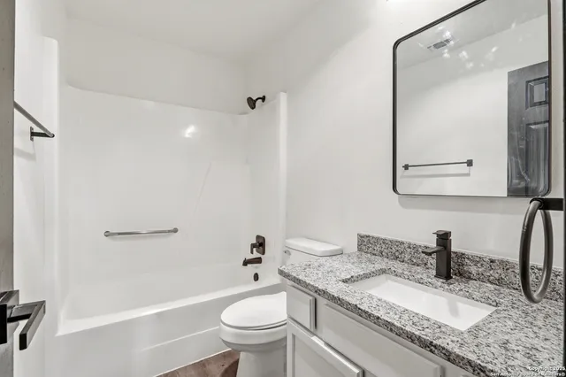 a bathroom with a granite countertop sink a toilet and a mirror