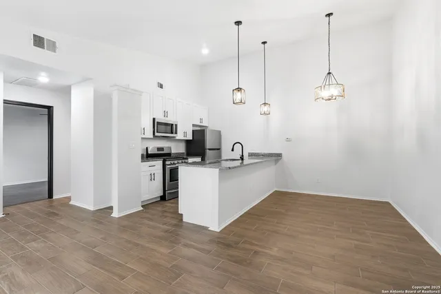 a kitchen with kitchen island a counter top space appliances and a ceiling fan