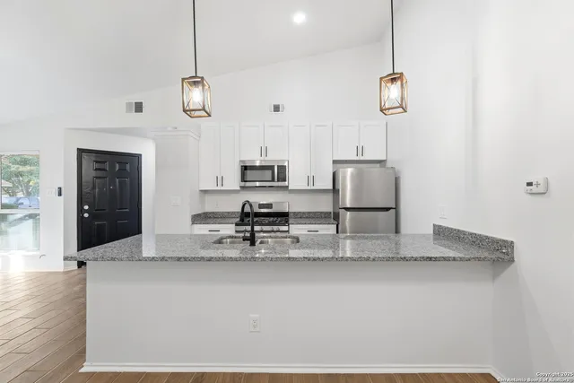 a kitchen with stainless steel appliances granite countertop a sink a stove and a refrigerator