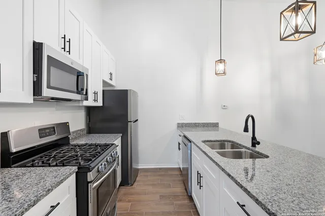 a kitchen with stainless steel appliances granite countertop a sink stove microwave and refrigerator