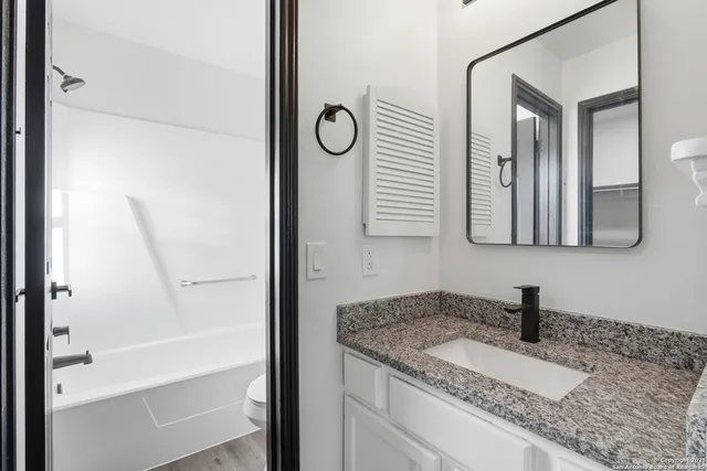 a bathroom with a granite countertop sink and a mirror