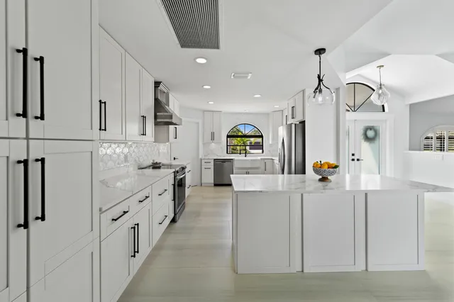 a kitchen with granite countertop white cabinets and stainless steel appliances