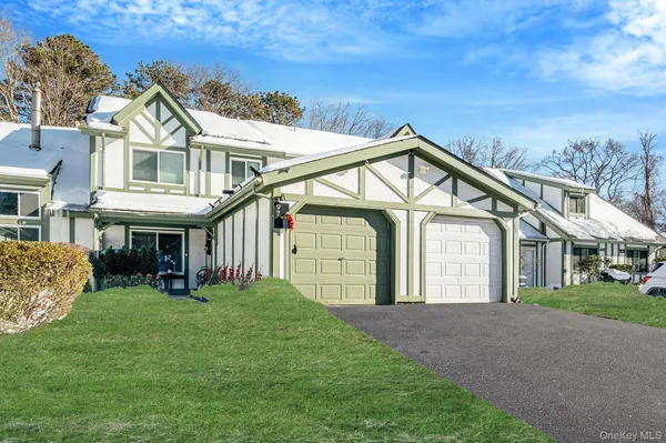 a view of a white house next to a yard with big trees