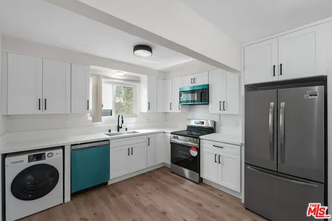 a kitchen with a sink a refrigerator and cabinets