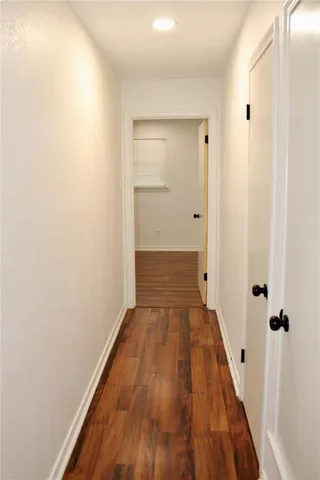 a view of a hallway with wooden floor and a bathroom