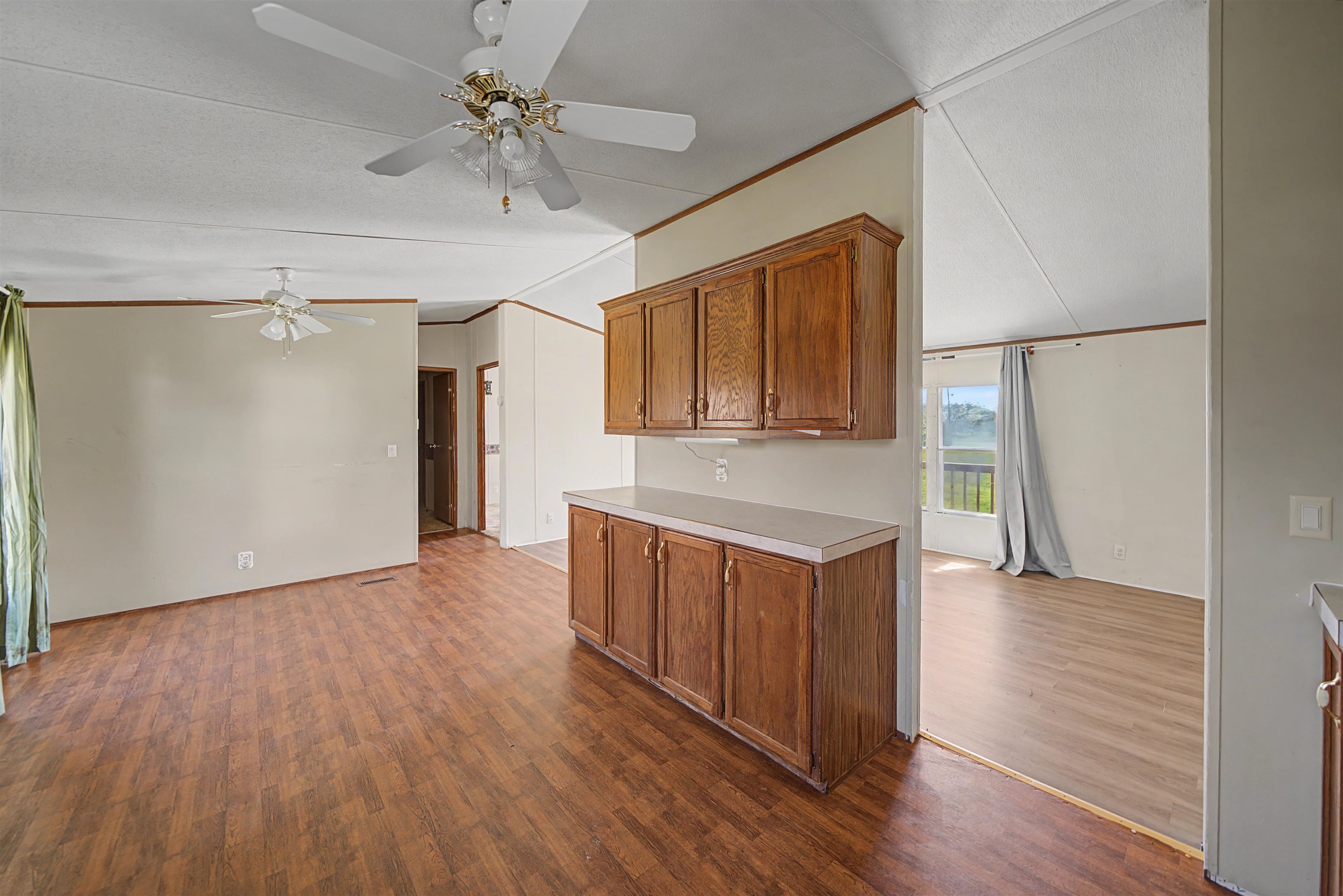 1788 Nichols Road Guys, TN 38339 - Photo 13 of 21 Kitchen featuring wood finish cabinetry, light countertops, dark wood-style flooring, crown molding, and lofted ceiling