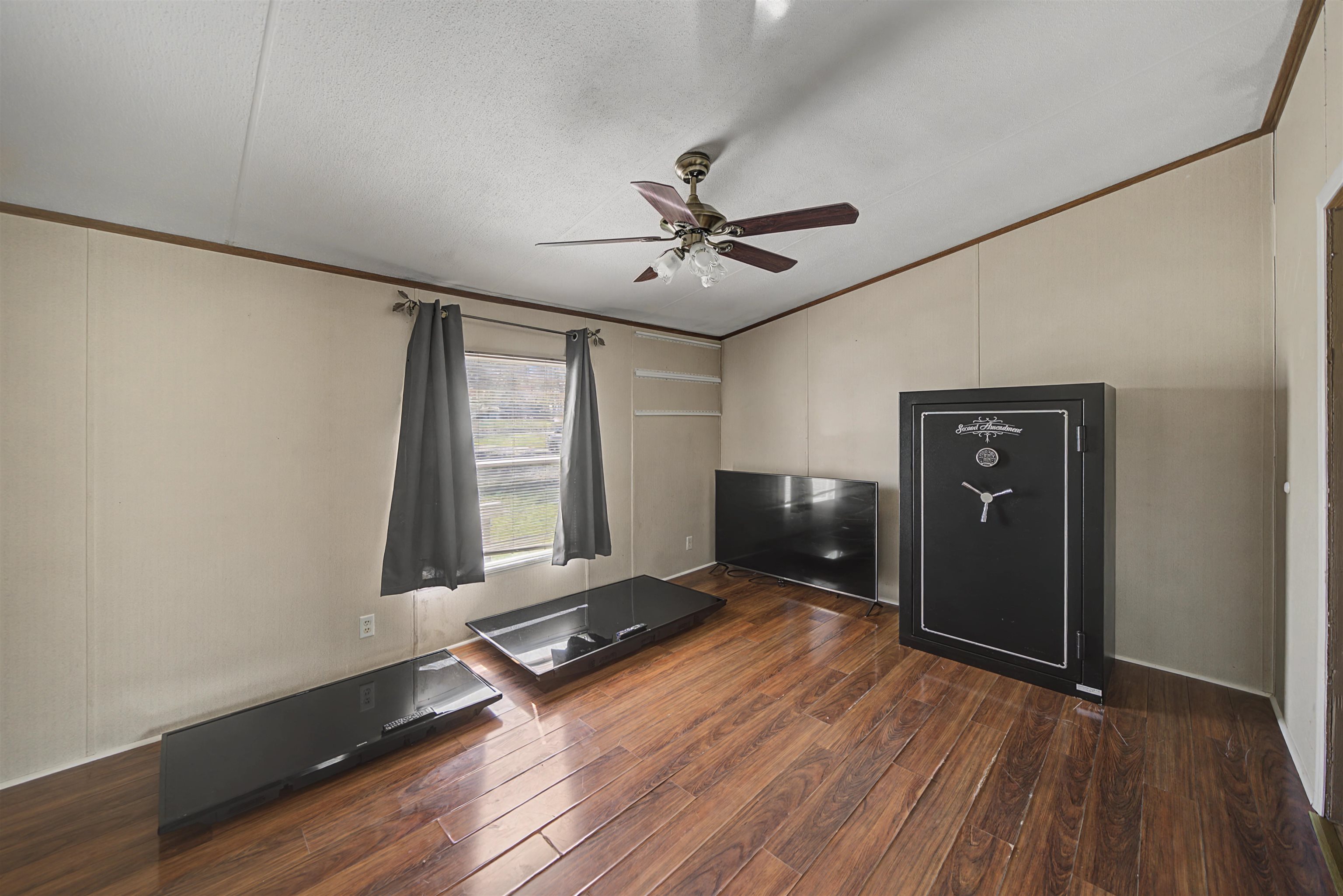 1788 Nichols Road Guys, TN 38339 - Photo 15 of 21 Unfurnished living room with a decorative wall, dark wood finished floors, crown molding, ceiling fan, and vaulted ceiling