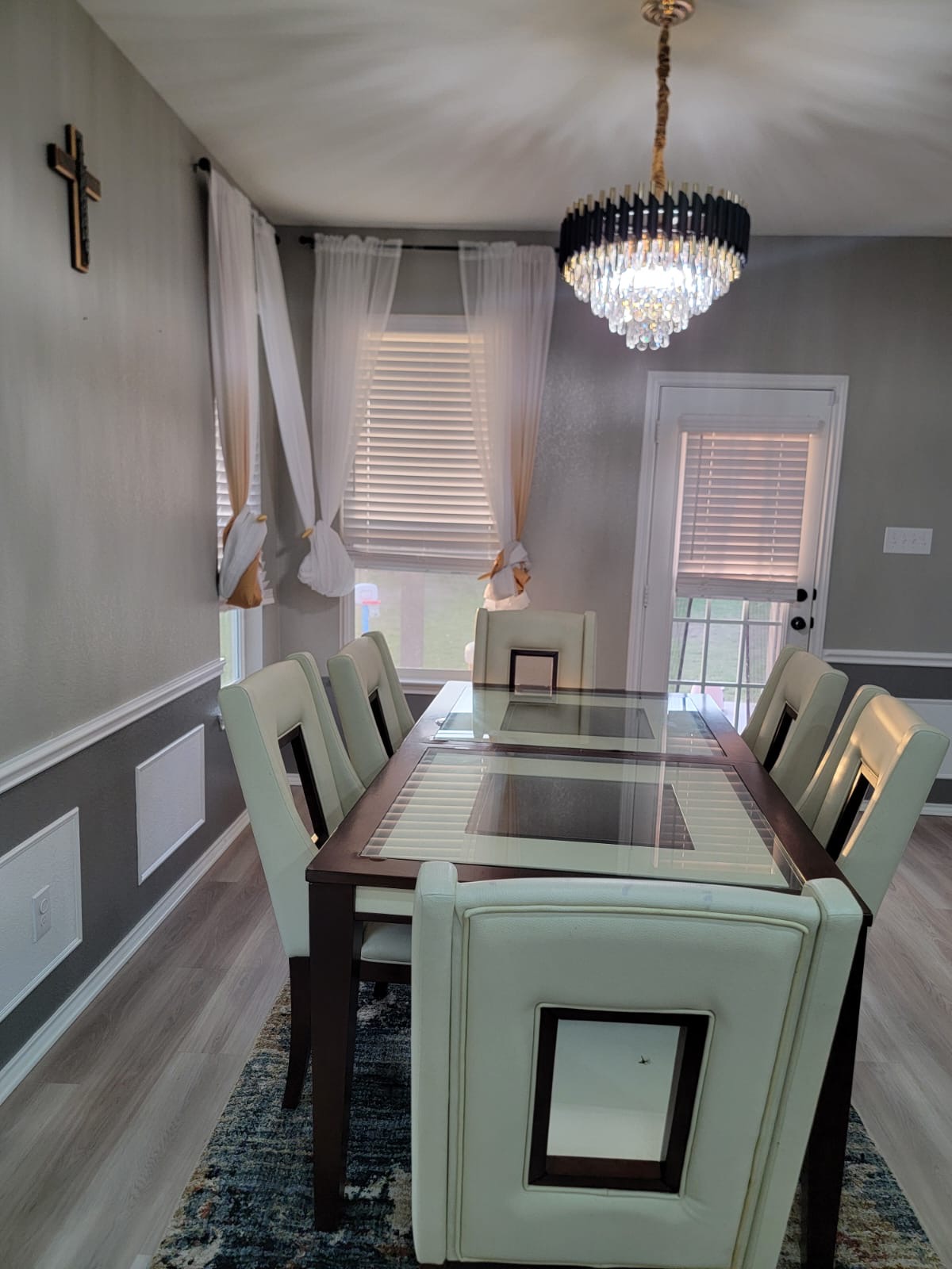 429 Unforgiven Lane Jarrell, TX 76537 - Photo 5 of 10 Dining area featuring wood-finish flooring, two-tone wall paneling, and a contemporary crystal chandelier