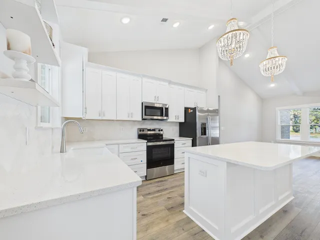 a kitchen with granite countertop a refrigerator oven a sink dishwasher and white cabinets with wooden floor