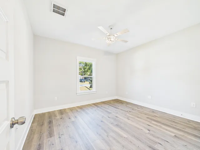 an empty room with wooden floor and window