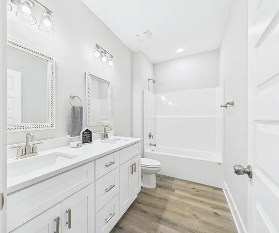 a bathroom with a double vanity sink toilet mirror and bathtub