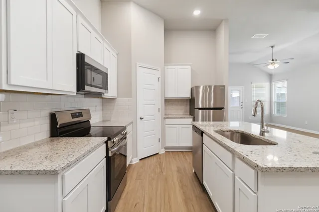 a kitchen with granite countertop a sink dishwasher stove and microwave with wooden floor