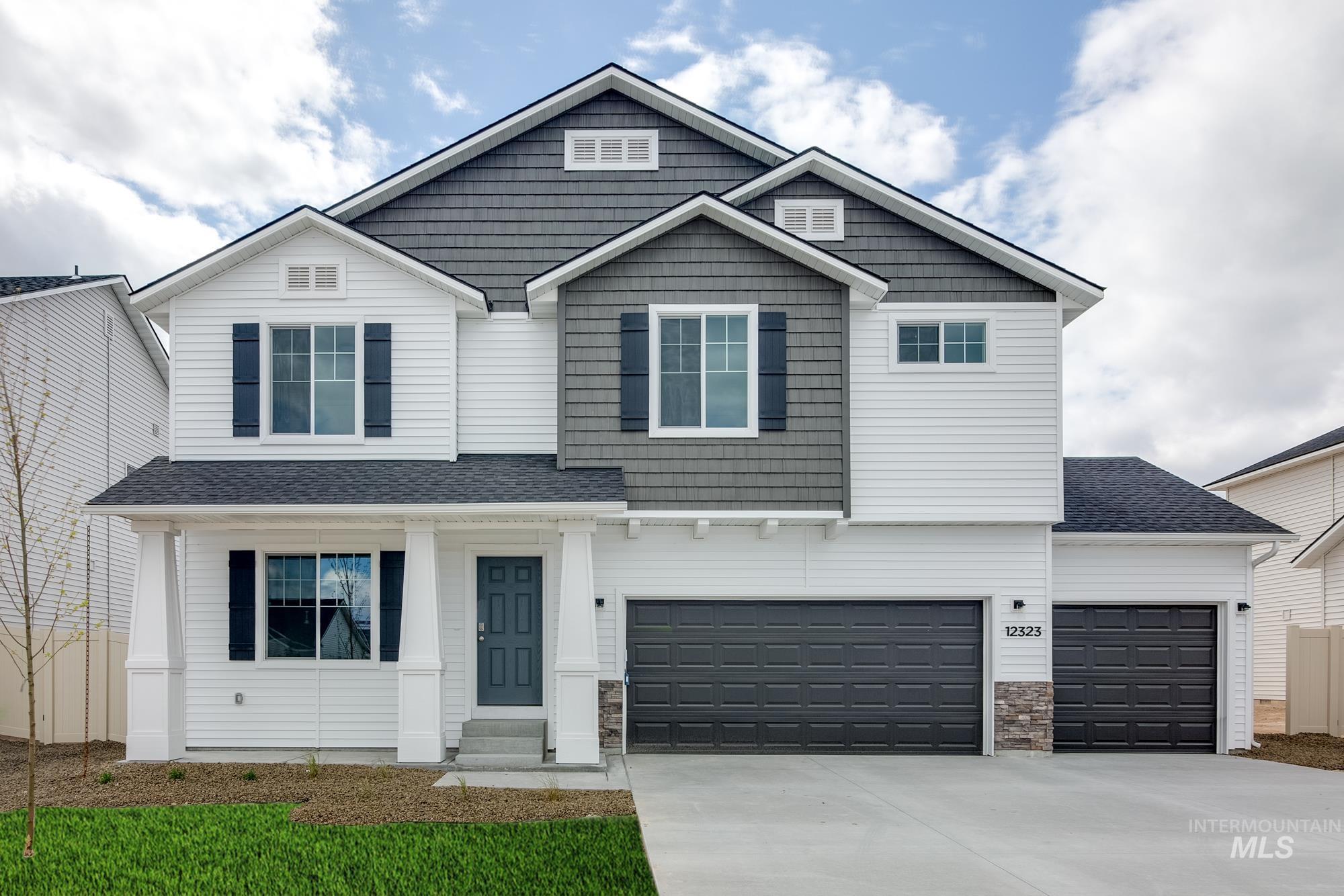 13333 Bank Street Caldwell, ID 83607 - Photo 1 of 29 Two-story exterior with white siding and gray shingle accents, multiple gables, a covered porch with white columns, and a two-car garage with an additional single-car garage
