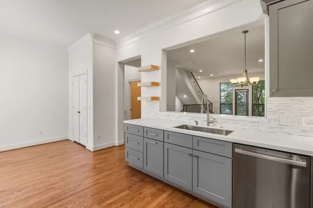 a large white kitchen with a sink and stainless steel appliances