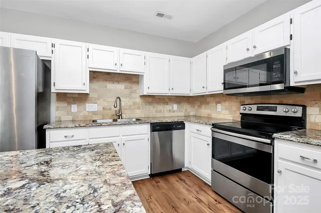 a kitchen with stainless steel appliances granite countertop a stove microwave and cabinets