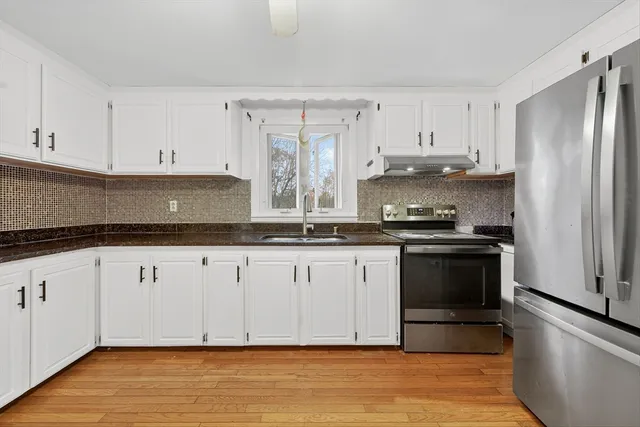 a kitchen with granite countertop a refrigerator sink and cabinets