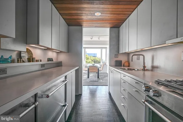 a kitchen with a sink dishwasher and white cabinets with wooden floor