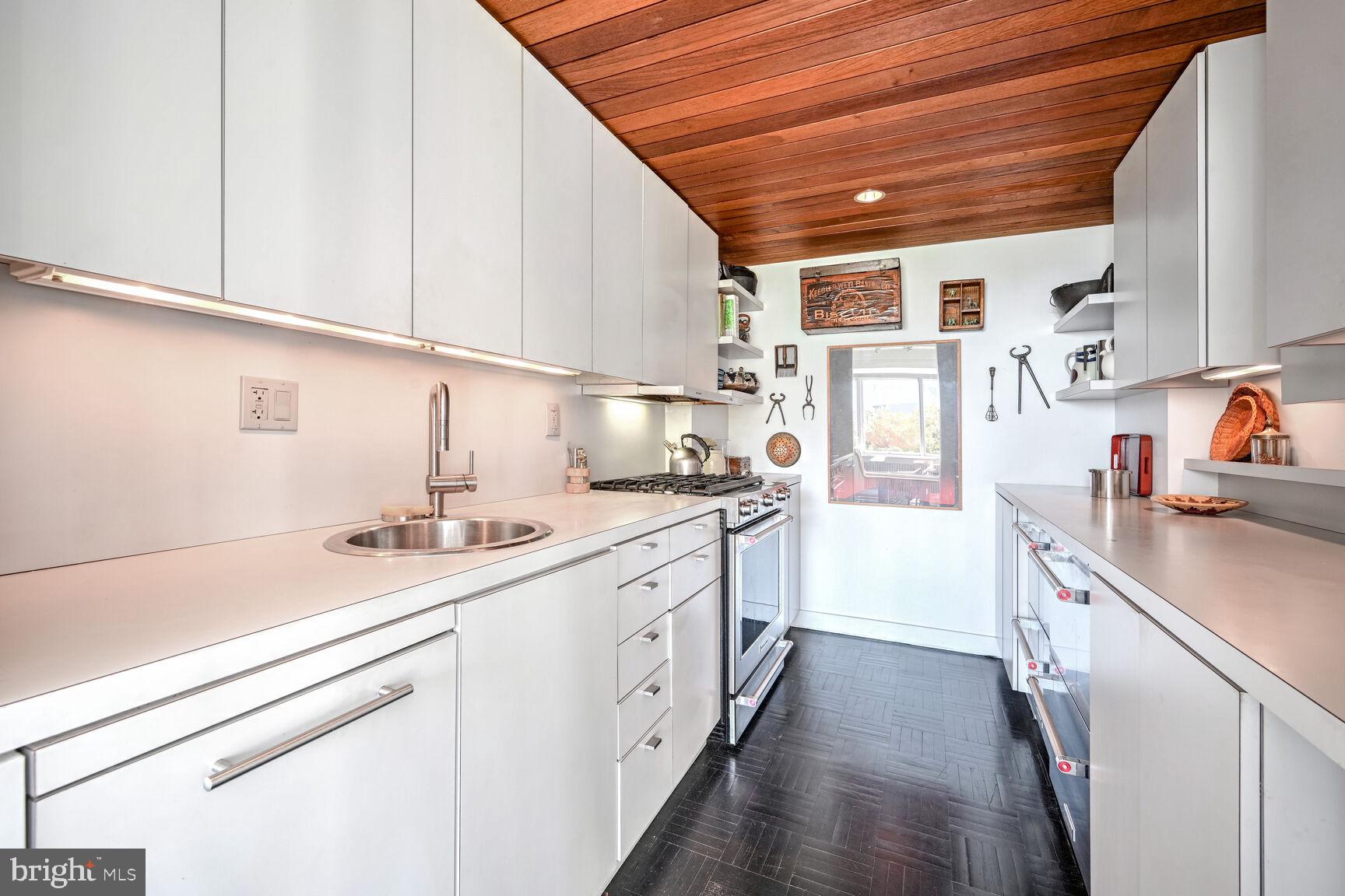 2475 Virginia Avenue Northwest, Unit 621 Washington, DC 20037 - Photo 21 of 49 a kitchen with a sink dishwasher and white cabinets with wooden floor